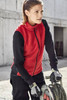 A red fleece vest worn by a woman, paired with black long sleeves and gloves, set in a work environment.