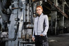 A grey ladies knitted fleece jacket with contrasting black details, worn by a model in an industrial setting.