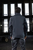A softshell jacket in dark grey, featuring a collar and visible stitching, displayed from the back.
