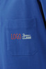 A blue polo shirt featuring a pocket with a logo, including scissors and a comb design.