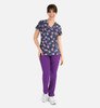 A woman wearing a navy V-neck printed top featuring colourful designs, paired with purple trousers. The outfit has a logo.