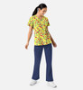 A woman in a yellow patterned V-neck print top and navy trousers, featuring a logo.