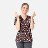 A woman in a black V-neck print top featuring a colourful pattern of hearts and various designs, smiling and gesturing with her hands.