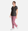 A floral-print women's V-neck top in black, paired with pink pants. The outfit features a logo on the top.