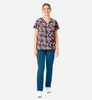 A floral print women's V-neck top in vibrant colours, paired with teal pants and worn with white shoes.