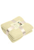 A folded fleece blanket in a light green colour, tied with a ribbon and featuring a label.