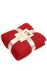 A red fleece blanket neatly folded and tied with a ribbon, featuring a tag with a logo.