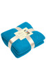 A folded turquoise fleece blanket tied with a ribbon, featuring a label and a logo.