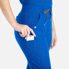 A pair of blue tapered leg pants featuring pockets, with a hand inserting a card into one of the pockets.