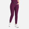 A pair of tapered leg pants in deep purple, featuring an elastic waist and side pockets, paired with white sneakers.