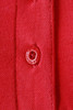 A close-up of a red ladies polo shirt featuring a button and textured fabric. The shirt has a logo on the fabric.