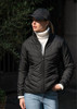 A black women's jacket featured with a high collar, worn with a white turtleneck and a black cap.