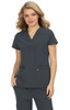 A woman wearing a grey scrub top with a v-neck and two front pockets, featuring a logo on one pocket.