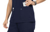 A navy blue top with pockets, featuring a hand reaching for a phone in one pocket. It has a logo on the fabric.