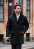 A stylish black puffer jacket with a hood, featuring a front zip and button closure, worn by a man outdoors.