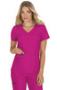 A woman wearing a bright pink scrub top with a V-neck and pockets. The scrub features a logo on the side.