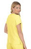 A woman models a bright yellow top, standing with her back to the camera and looking over her shoulder. The top has a logo.