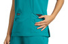 A teal top featuring pockets, with a patterned fabric visible from one pocket. The garment has a logo tag.