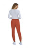 A pair of rust-coloured jogger pants displayed on a model wearing a white top, with a logo visible on the pants.