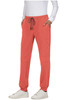 A person stands in coral jogger pants featuring pockets and a drawstring, paired with white shoes.
