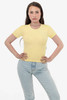 A yellow short-sleeve ribbed t-shirt displayed on a model, paired with light blue jeans. The shirt features branding.