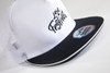 A white and black trucker cap featuring a mesh back and a curved brim, with a logo on the front.