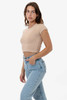 A model wearing a beige cap sleeve baby rib crop top paired with light blue jeans. The top features a fitted design.