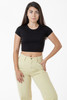 A black cap sleeve crop top paired with light beige trousers, featuring a model standing confidently.