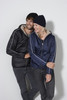 A man and woman wear matching jackets in black and navy, each sporting a knitted beanie, in a casual pose.
