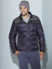 A man wearing a grey Melange beanie and a black puffer jacket, posing against a light blue wall.