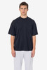 A black short sleeve pocket tee with a relaxed fit and a casual style, worn with grey pants. The shirt features a logo.