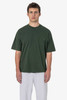 A green short sleeve t-shirt featuring a pocket, worn by a model with grey pants. It has a logo on it.