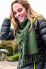 An elegant green scarf draped around a smiling woman, paired with a puffy black jacket.