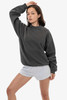A woman poses wearing a grey heavy fleece pullover and light grey shorts, showcasing a casual style.