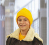 A yellow knitted beanie worn by a smiling child, paired with a brown jacket featuring a fluffy collar.