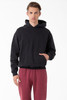 A heavy fleece hooded pullover in black, featuring a front pocket and a relaxed fit, paired with maroon pants.