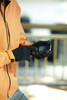 A person wearing black touch-screen knitted gloves uses a mobile device while dressed in an orange jacket.