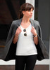 A woman in a grey blazer over a white T-shirt and black pants, styled with sunglasses and accessories.