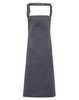 A dark grey Chino Cotton Bib Apron with pockets and a neck strap, featuring a logo.