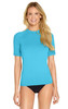 A turquoise adult short sleeve rash shirt with UPF 50+ protection, modelled by a woman. It features a branding logo.