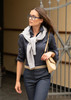 A women’s button-up shirt in navy blue, paired with a light grey sweater tied around the shoulders and denim trousers.