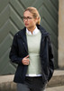 A woman wearing a black rain jacket over a light green sweater, paired with a collared shirt and glasses.