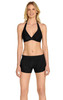 A woman in a black bikini top and black swim shorts, featuring a waistband and a simple design.