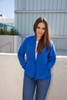 A blue polar fleece jacket with a zip, featuring side pockets, worn by a model outdoors.