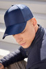 A navy blue 6 panel cap is worn by a person, showcasing its sleek design and fitted structure.