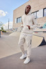 A men's interlock hoodie in beige, paired with matching pants, features a logo and a relaxed fit.