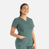 A teal women's curved V-neck top with short sleeves and pockets, featuring a logo on the chest.