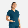 A teal women's curved V-neck top with short sleeves and pockets, featuring a branding logo.