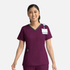 A purple women's scrubs top with a double V-neck design, featuring a patch pocket and a badge holder.