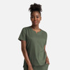 A woman wears a green notched crew neck top with short sleeves and a relaxed fit, featuring a subtle branding.